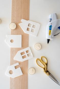 some craft supplies are laying out on a white surface with scissors and buttons next to them