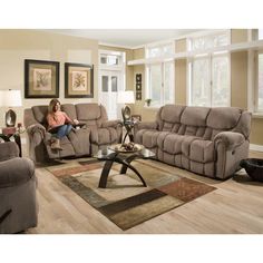 a woman sitting in a living room with two recliners and a coffee table