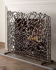 an intricately designed metal screen with oranges in the center on a wooden floor