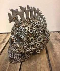 a skull made out of wrenches and gears on top of a wooden table with a white wall in the background