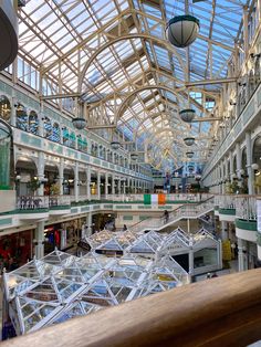 the inside of a shopping mall filled with lots of glass and metal structures hanging from the ceiling