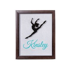 the silhouette of a ballerina is framed in a wooden frame with blue lettering that reads, krisley