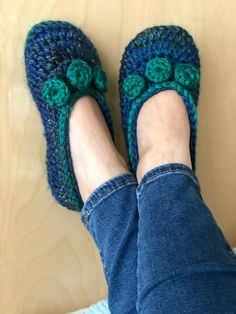 someone is wearing blue and green crocheted slippers with bows on the toes