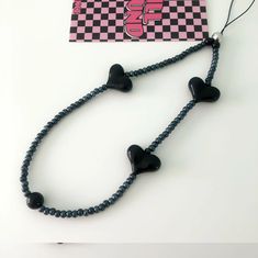 the black heart beads are attached to a necklace with a pink tag hanging from it