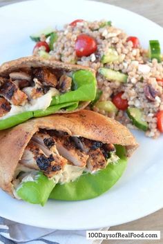 two wraps filled with meat and vegetables on a white plate next to a side salad