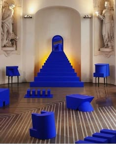 a room filled with lots of blue furniture next to two large statues and sculptures on the walls