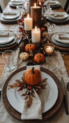 a table set for thanksgiving dinner with candles, plates and napkins on the table