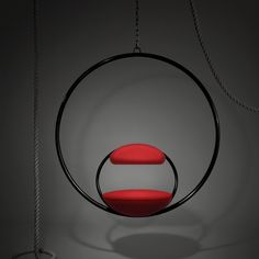 a circular object with two red seats hanging from it's sides in the dark