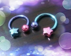 three different colored nose rings sitting on top of a purple and blue background with lights in the background