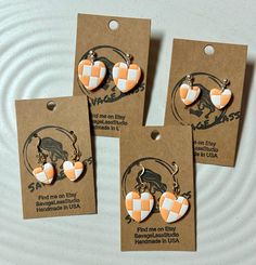 three orange and white heart shaped earrings on brown tags