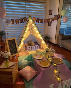 a teepee tent set up for a birthday party with plates and napkins on the table