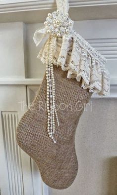 a stocking hanging from the ceiling with pearls and lace on it's side