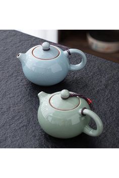 two teapots sitting on top of a table next to each other with handles