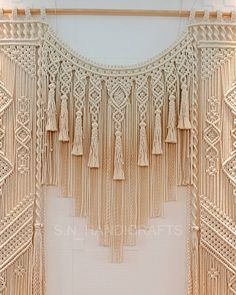 a wall hanging made out of macrame and tassels on a white wall