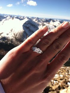 a person's hand with a diamond ring on top of a mountain