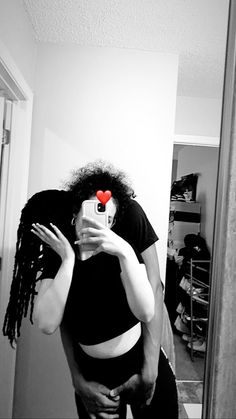 a woman is taking a selfie in the mirror with her cell phone while wearing a red heart on her forehead