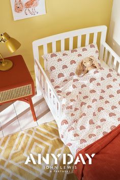 a baby crib with a stuffed animal in it's bed next to a yellow wall