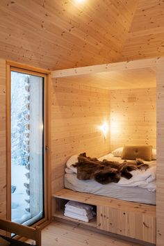 a bed sitting inside of a wooden room next to a window