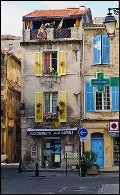 an old building with yellow shutters on the windows and balconies above it