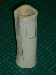 a small white vase sitting on top of a green table next to a knife board