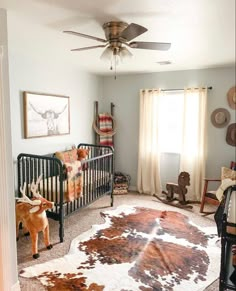 a baby's room with a cow hide rug on the floor and a ceiling fan