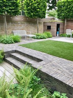 a garden with grass and brick steps leading up to the front door