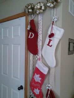 christmas stockings hanging on the wall in front of a door with silver bells attached to them