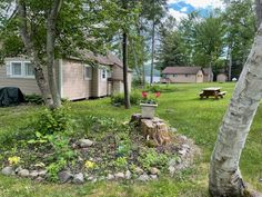 a small cabin in the woods with picnic tables and benches around it, near a lake