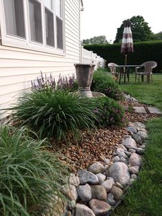 a garden with rocks and plants next to a house