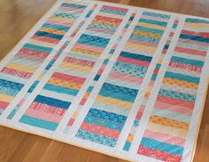 a colorful quilt is laying on the floor in front of a wooden flooring area