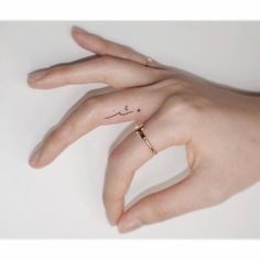 a person's hand with a small tattoo on it and a ring in the middle