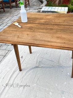 a wooden table sitting on top of a patio next to a potted plant in a vase