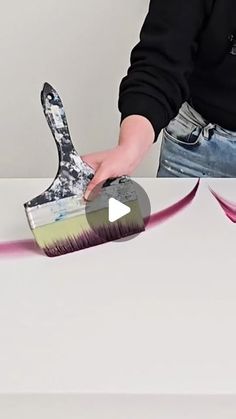 a person holding a paintbrush with pink streaks coming out of it and the brush is being held by someone's hand