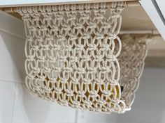 a close up of a crocheted curtain hanging from a hook on a wall