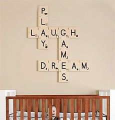 a baby in a crib with scrabble tiles on the wall above it