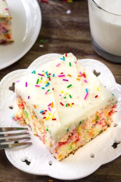 a slice of cake with white frosting and sprinkles on a plate