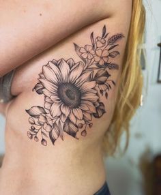 a woman's stomach with a flower tattoo on her side and the bottom part of her body