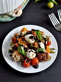 a white plate topped with lots of food on top of a black table next to silverware