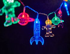 an assortment of colorful lights that look like toy rockets and space shuttles are hanging on a string