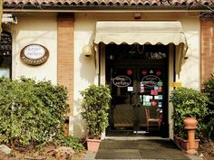 an entrance to a restaurant with potted plants and signs on the front door window