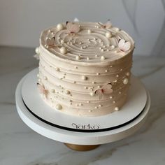 a white cake sitting on top of a table next to a plate with flowers and pearls