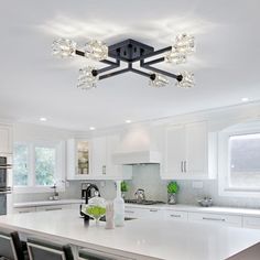 a kitchen with white cabinets and an island in the middle is lit up by lights