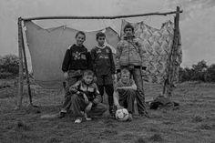 black and white photograph of four children posing in front of a tent with a soccer ball