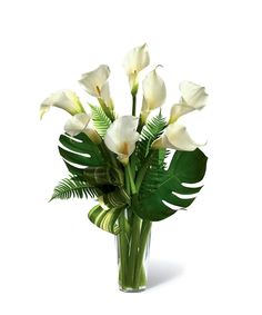 a vase filled with white flowers and green leaves