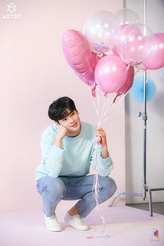 a person kneeling down with some balloons in front of her and posing for the camera