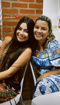 two women sitting next to each other smiling