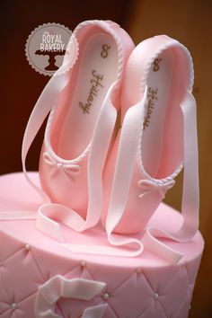 a pink cake with two pairs of ballet shoes on top