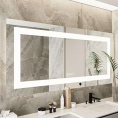 a bathroom with marble walls and white counter tops, two sinks and a large mirror on the wall