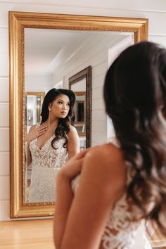 a woman in a wedding dress looking at herself in the mirror and getting ready for her big day