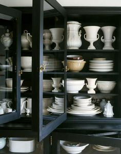 an open book shelf filled with lots of white dishes